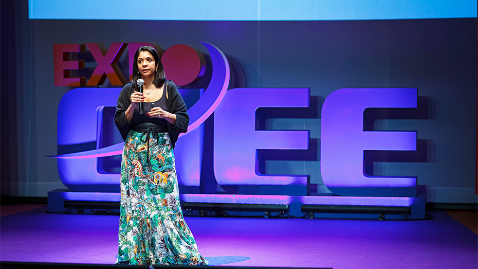 Fundo com o logo da Expo CIEE em 3D, a frente temos a imagem de uma mulher falando com um microfone na mão.