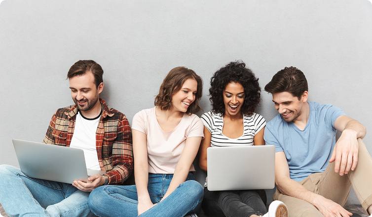 Quatro jovens estudantes sentados lado a lado olhando para a tela do notebook